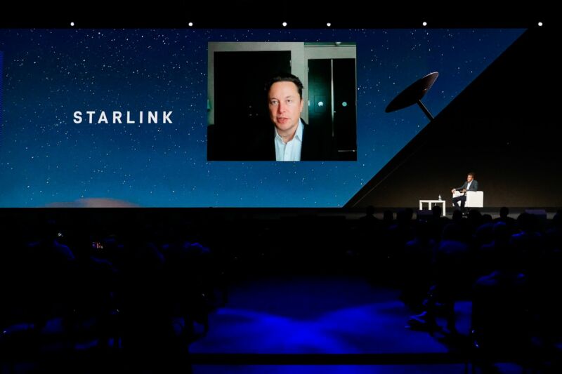 SpaceX CEO Elon Musk appears on a giant video screen while he discusses Starlink.