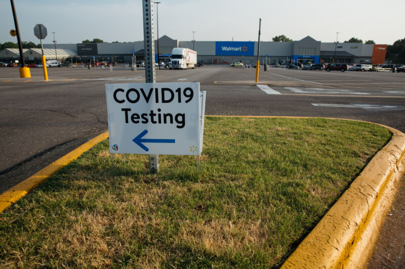 A plastic sign is attached to a pole in a parking lot.