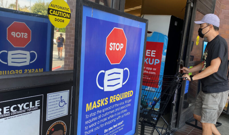 Signs Requiring Masks Line The Entrance To A Grocery Store.