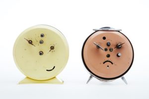 The backs of two vintage alarm clocks look like happy and sad face