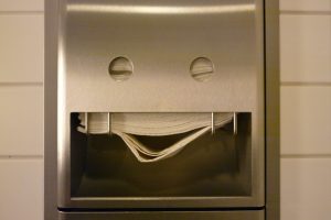 A towel dispenser in a public washroom appears to be smiling.