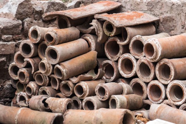 Anciens Tuyaux D’égout Romains Empilés Contre Un Mur De Pierre