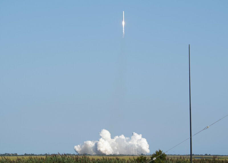 A rocket leaves a cloud of smoke behind as it launches it a blue sky.