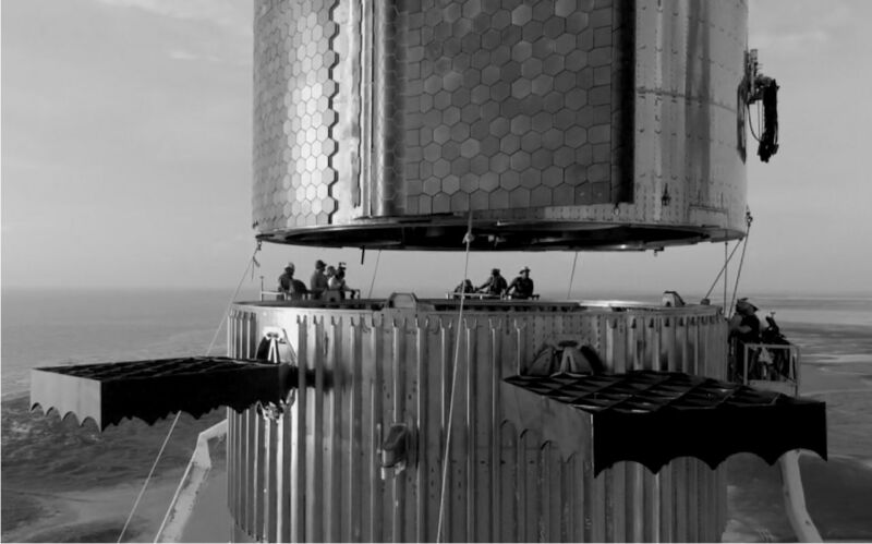 Workers perform a fit test with Starship (above) and the Super Heavy booster.