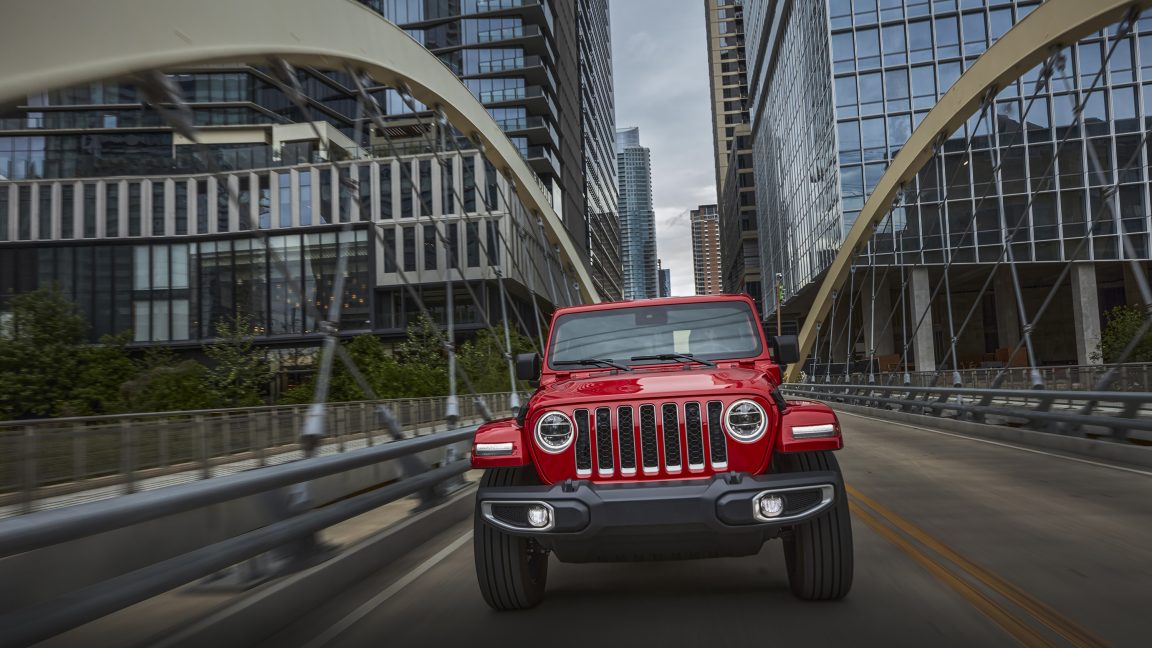 A red 2021 Jeep Wrangler Sahara 4xe crosses a bridge in Austin