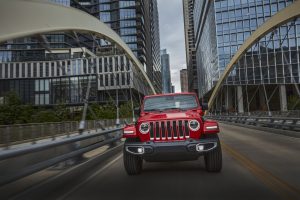 A red 2021 Jeep Wrangler Sahara 4xe crosses a bridge in Austin