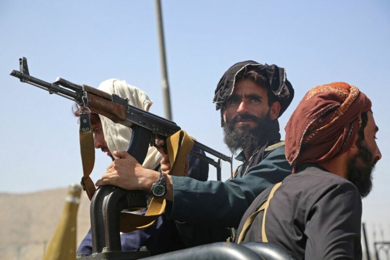 Taliban fighters stand guard in a roadside vehicle in Kabul on August 16, 2021.