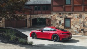 A red Porsche 911 GTS parked outside a house