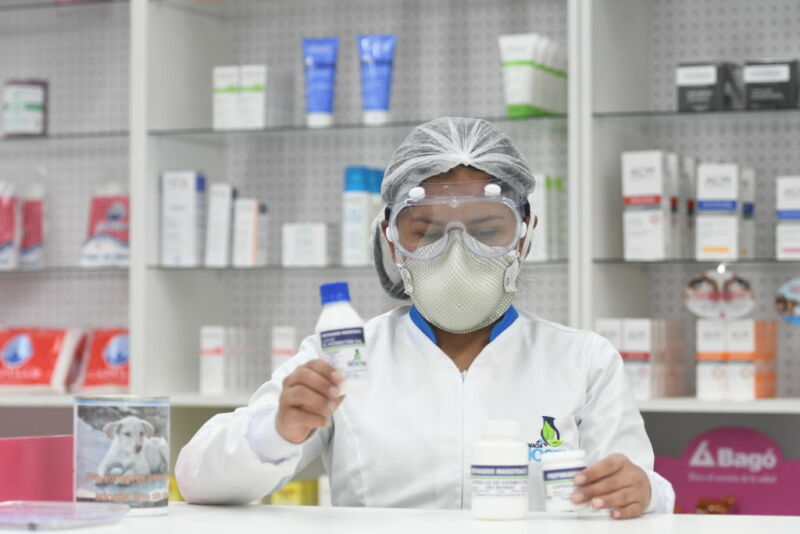 Image of a woman in protective clothing dispensing pills.