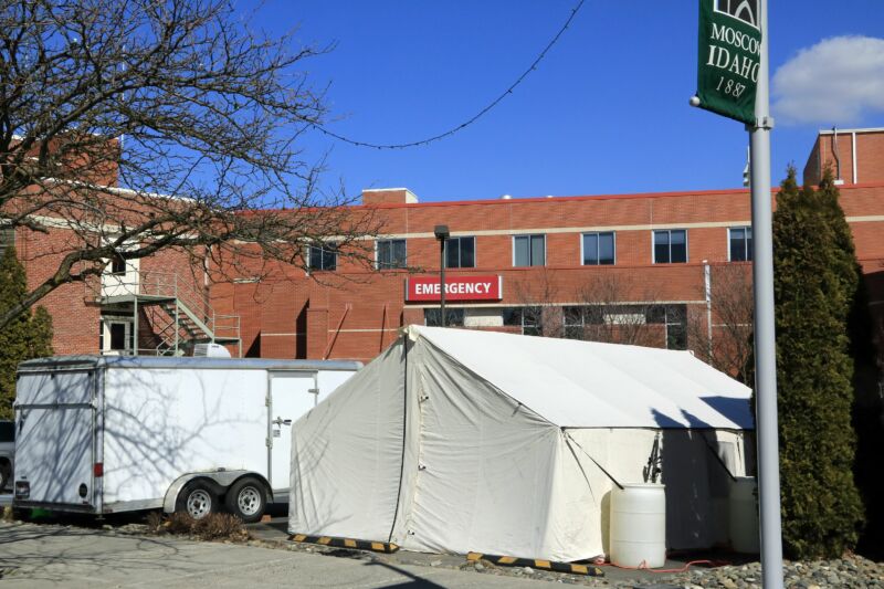 Large tents set up outside a brick building.