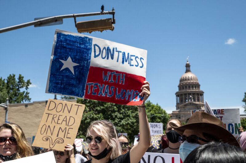 Protesters hold up signs as they march down Congress Ave at a protest outside the Texas state capitol on May 29, 2021 in Austin, Texas. Thousands of protesters came out in response to a new bill outlawing abortions after six weeks was signed into law by Texas Governor Greg Abbot.