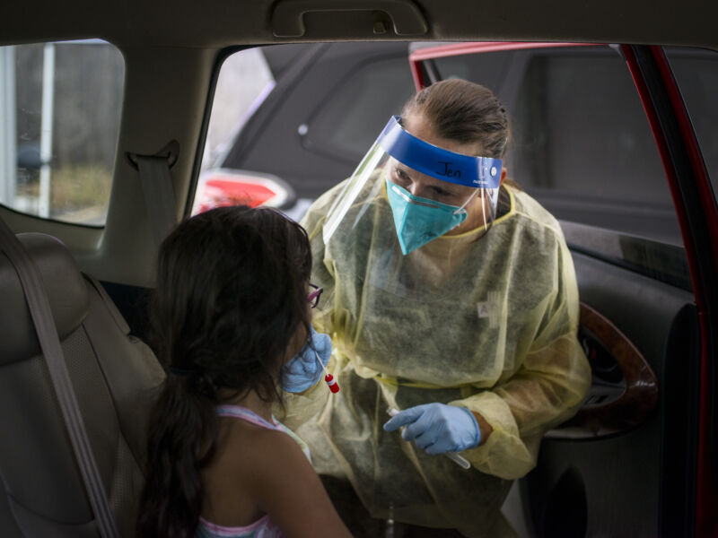 A health care worker administers a COVID-19 test to a child at the Austin Regional Clinic drive-thru vaccination and testing site in Austin, Texas, US, on Thursday, Aug. 5, 2021. 