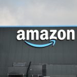 Outside view of a warehouse with a large Amazon logo on the side of the building.