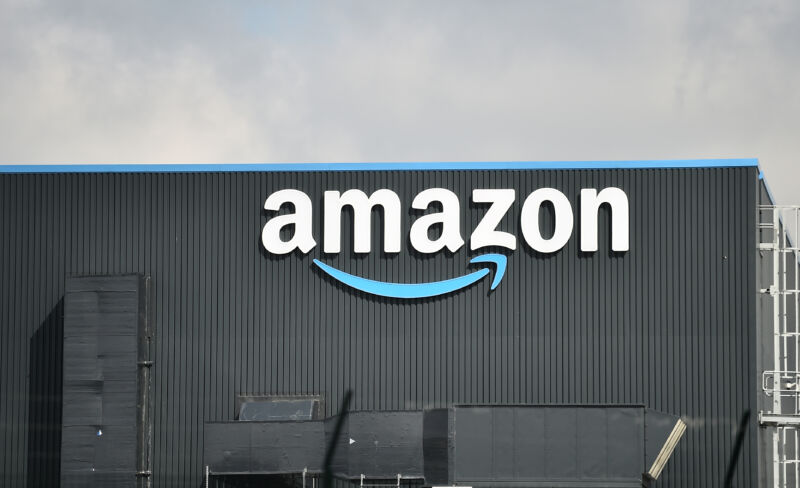 Exterior view of a warehouse with a large Amazon logo on the side of the building.