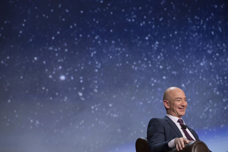 Jeff Bezos at a space conference, sitting in front of a picture of the stars in the night sky.