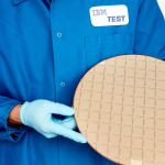A computer component in the hands of a gloved IBM employee.