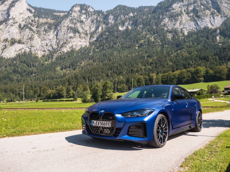 A Blue Bmw I4 Next To Some Mountains