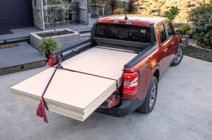 A Ford Maverick with a load of 4x8 plywood in the bed