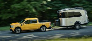 A yellow Ford Maverick towing a small Airstream trailer