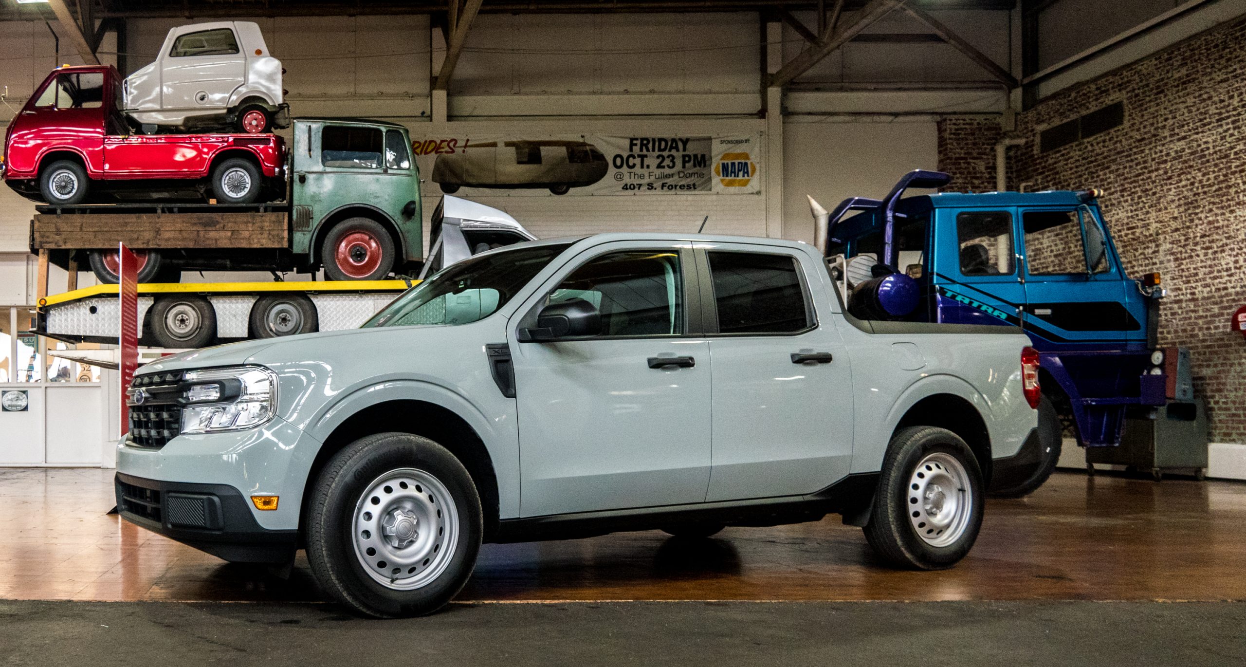 A Ford Maverick truck parked in front of big and small trucks at the Lane Motor Museum