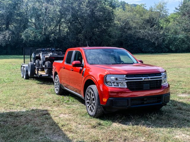 A Ford Maverick with a trailer loaded with two ATVs