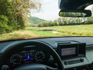 The view from a Ford Maverick looking out over a pond and a dirt track