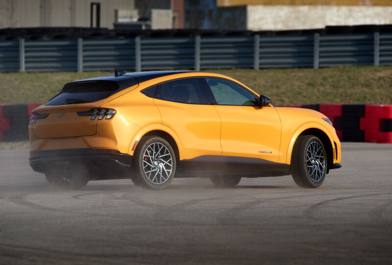 An orange Ford Mustang Mach-E GT burning rubber at an autocross