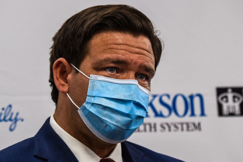A man in a suit and a medical mask.