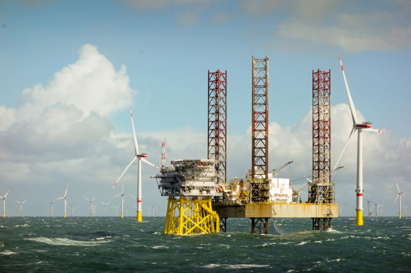 Image of a construction platform above the waves amidst wind turbines.