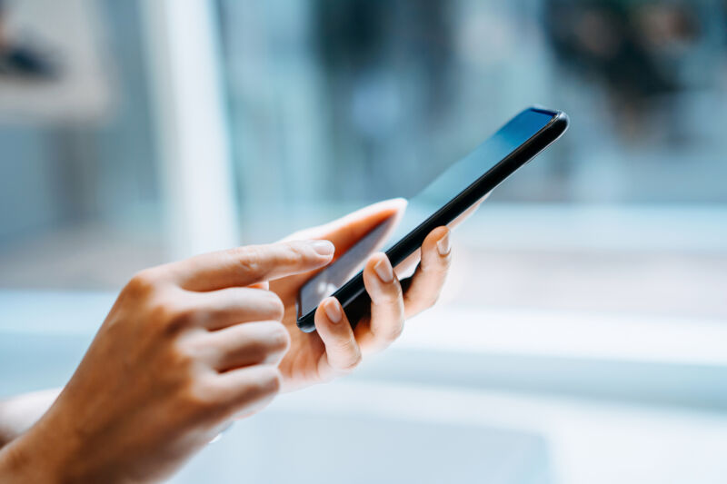 A woman's hand holding a smartphone.