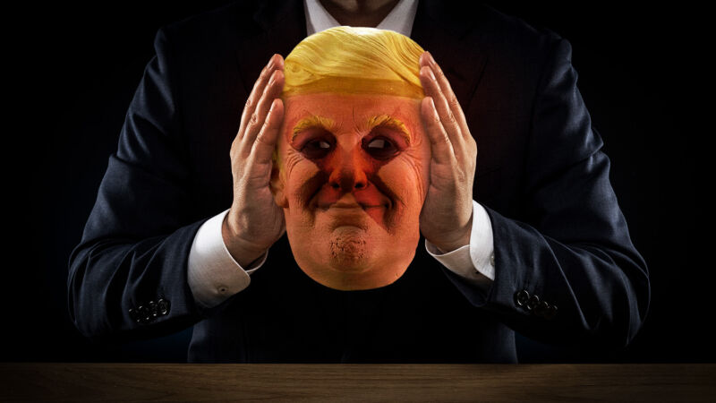 Uma figura sombria segura a máscara de Donald Trump.
