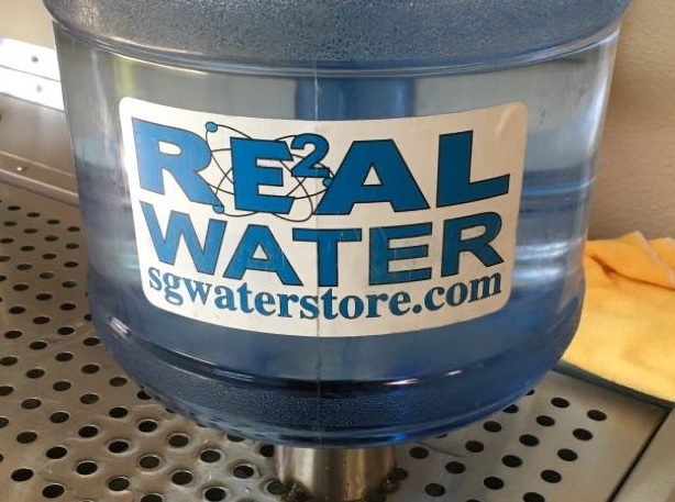 Blue-tinted jug of Real Water-branded water.
