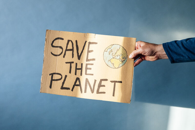 Man's hand holding a cardboard sign that says SAVE THE PLANET