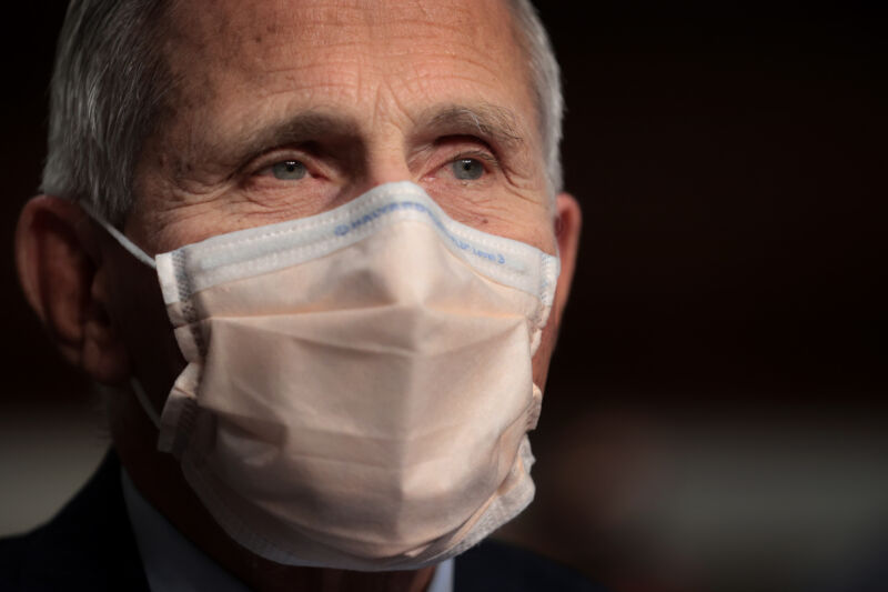 A white-haired man in a face mask.