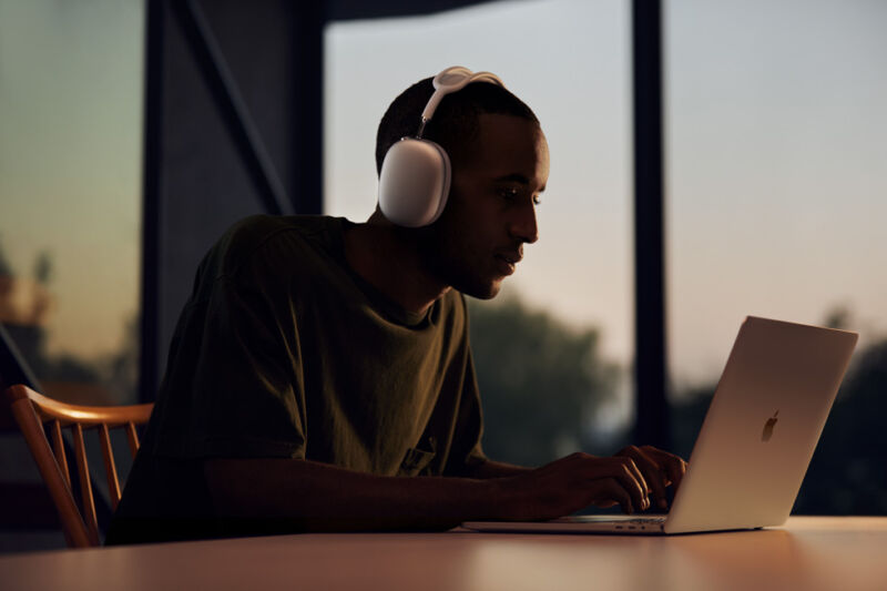 A man wears over-ear headphones while working at a laptop