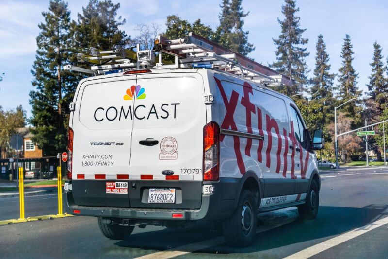A Comcast Xfinity utility van driving down a street.
