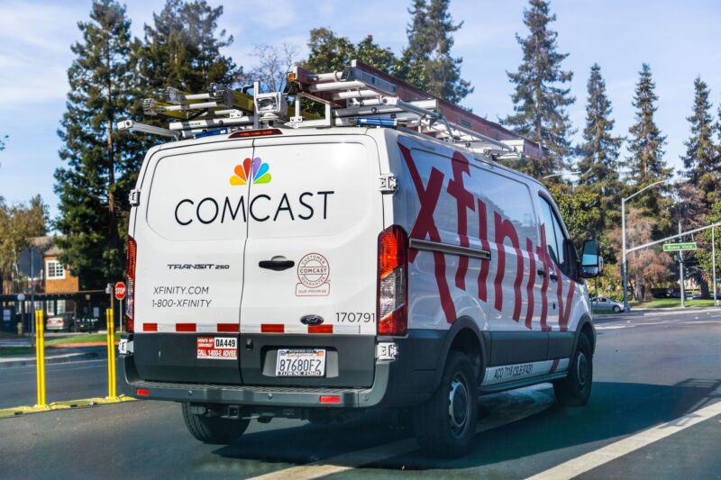 A Comcast Xfinity work  van driving down   a street.