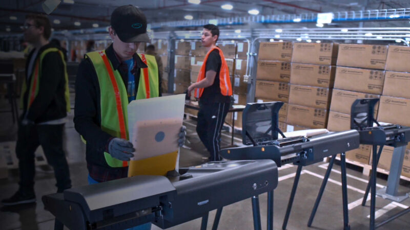 Workers and voting machines in a Smartmatic warehouse.