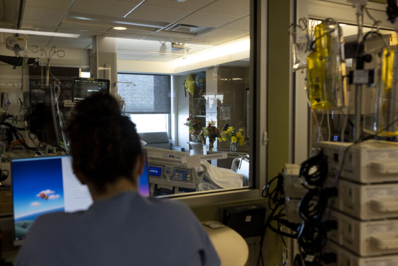 A nurse in the ICU looks into a COVID patient's room filled with flowers and balloons at CentraCare St. Cloud Hospital in St. Cloud, Minn., on Tuesday, Nov. 23, 2021.