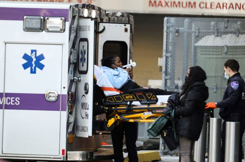 A woman on a stretcher is pulled from an ambulance.