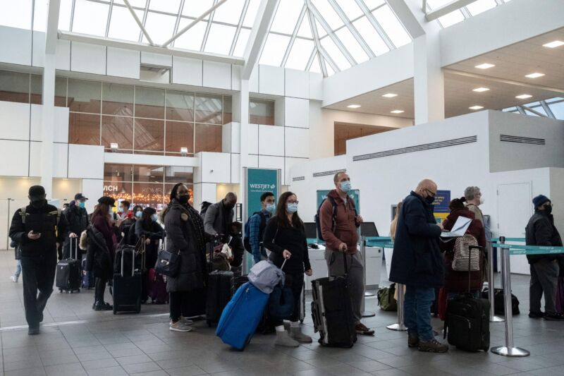 Travelers wait in line to check-in at LaGuardia Airport in New York, on December 24, 2021. -On Christmas Eve, airlines, struggling with the Omicron variant of Covid-19, have canceled over 2,000 flights globally, 454 of which are domestic, into or out of the US.