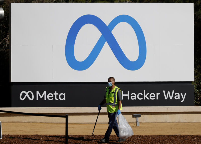 A worker picks up trash in front of the new logo in front of Meta