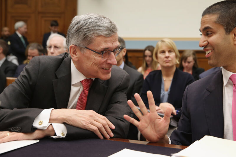 Technology Then-Federal Communications Commission Chairman Tom Wheeler and FCC Commissioner Ajit Pai smiling and talking to each other before a Congressional hearing.