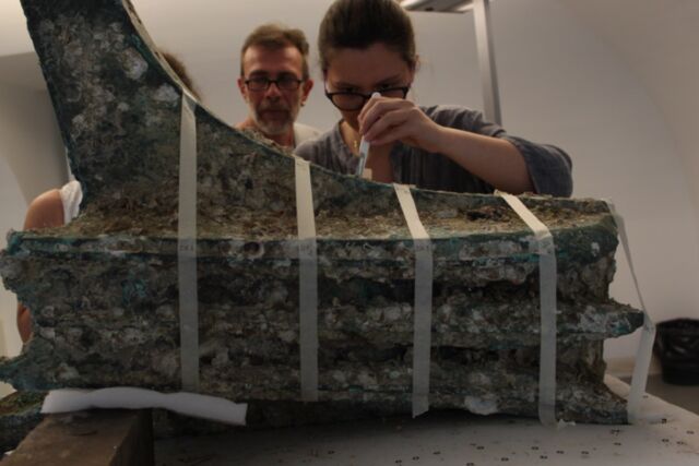 Researchers take samples of marine animals from the ship's bronze ram.
