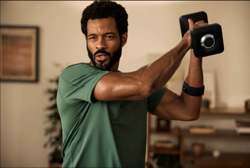 Promotional image of a man wearing a Peloton arm band working out.