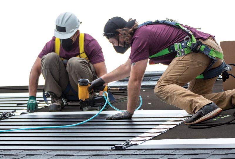 Installers nail GAF Energy's new solar shingles to a demonstration house.