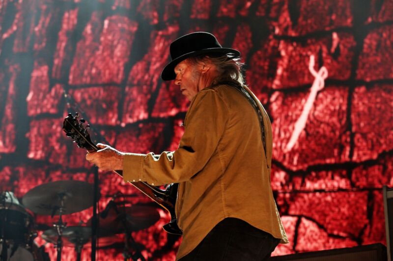 Neil Young playing guitar on stage.