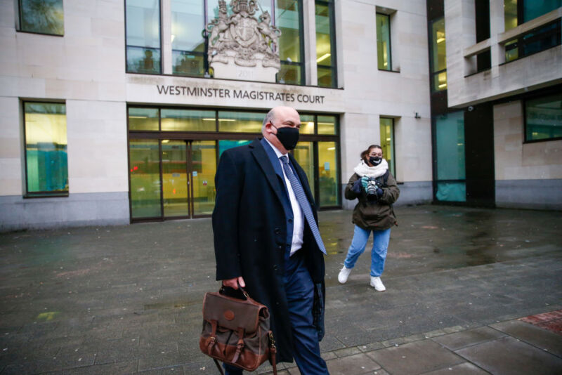 A man in a mask and a business suit walks away from an official building.