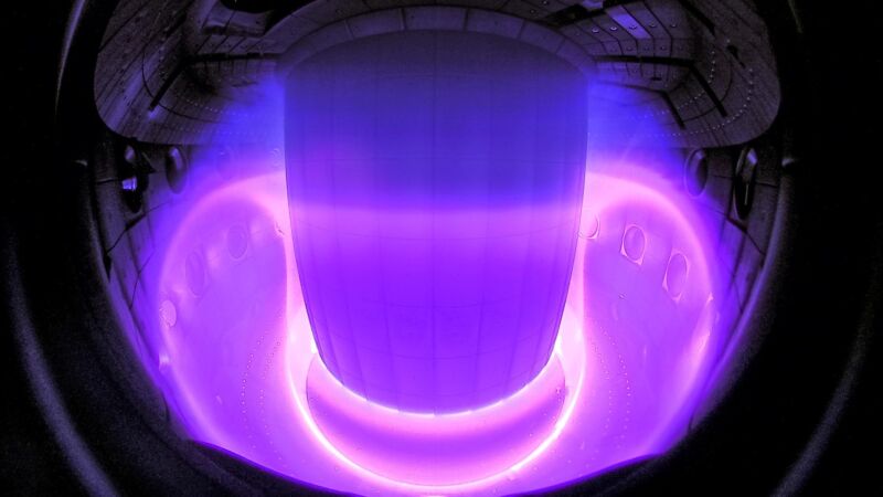 A dark space with a toroidal material that glows purple.