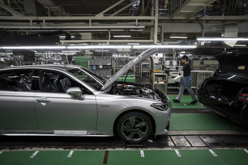 A worker walks near a Toyota Motor Corp Crown vehicle manufactured on the production line of the company's Motomachi factory on July 30, 2018, in Toyota, Japan.